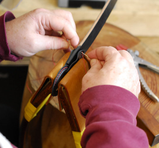 Hand sewing English bridle leather in a clam